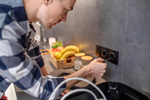 Man using a screwdriver to replace wall switch plate
