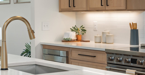 Modern kitchen with white counters, gold faucet, and switch plate